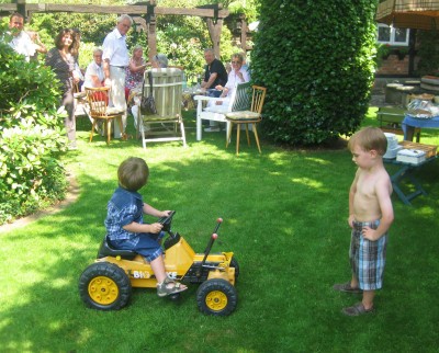 two boys in German garden, one on toy tractor