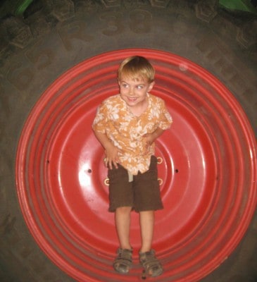 boy standing in tractor wheel